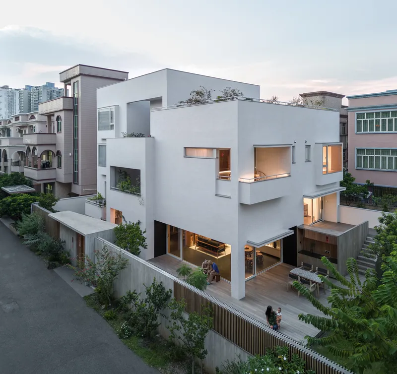 Elevated view of the white stucco facade with terraces and timber-screened fence at dusk