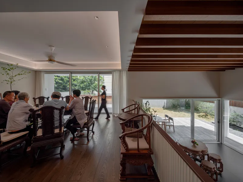 Double-height dining area with exposed timber beams and sliding glass walls opening to a terrace