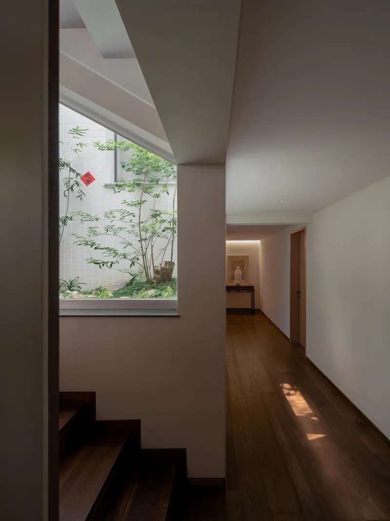 Upper floor hallway with timber flooring and window framing a small courtyard garden with bamboo