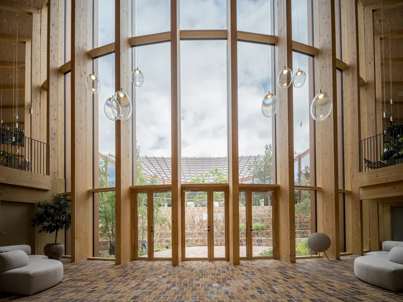 Double-height atrium with floor-to-ceiling timber-framed windows and suspended glass pendant lights