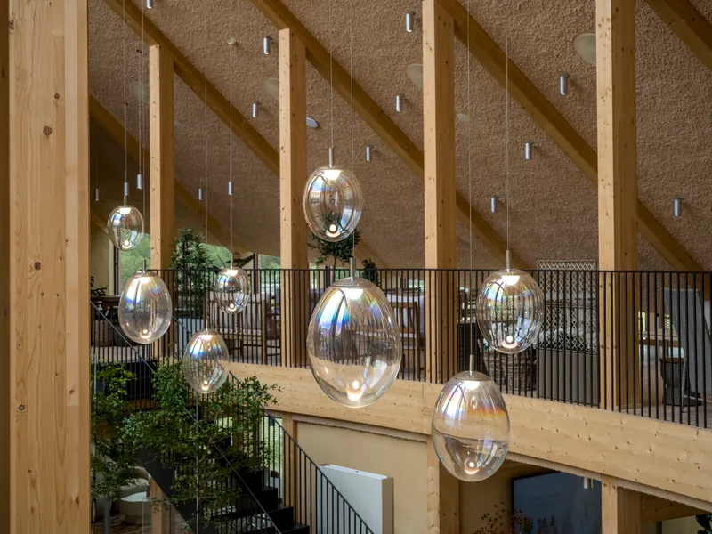 Mezzanine balcony with metal railing and clustered glass pendant lights against hempcrete and timber structure