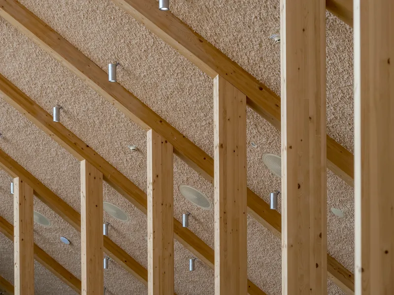 Upward view of exposed timber beams and textured ceiling panels with integrated cylindrical light fittings