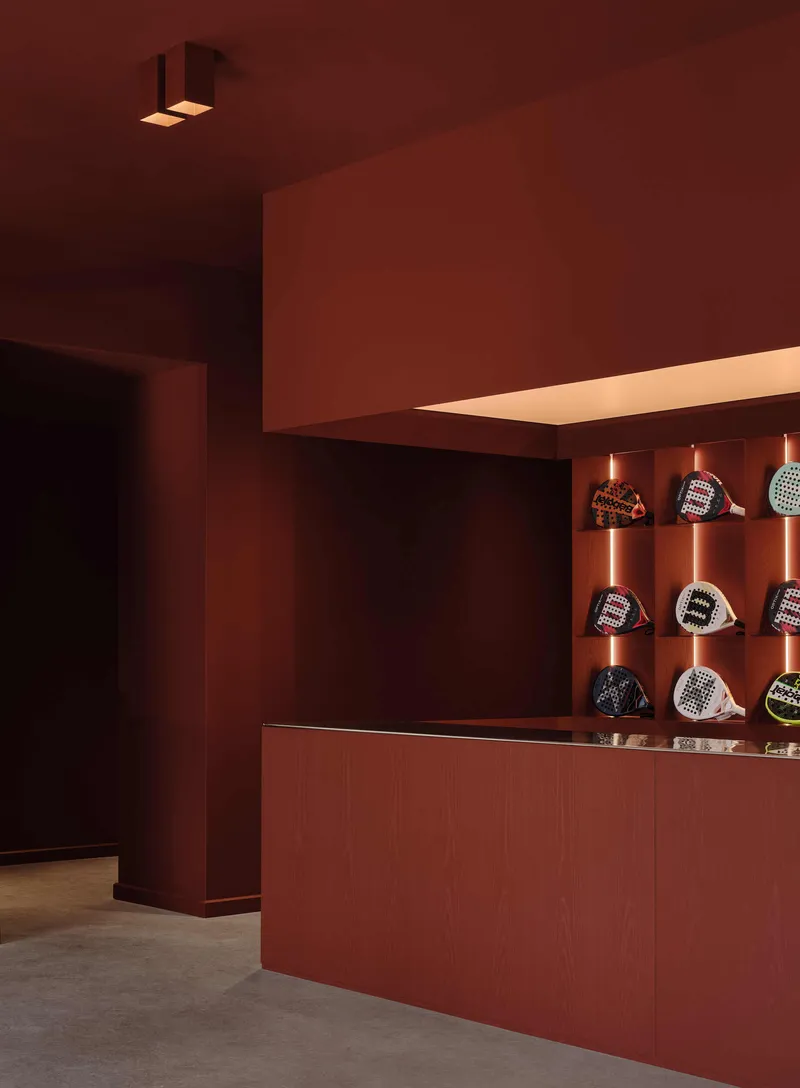 Display niche with backlit shelves holding merchandise beneath a floating illuminated soffit in terracotta tones