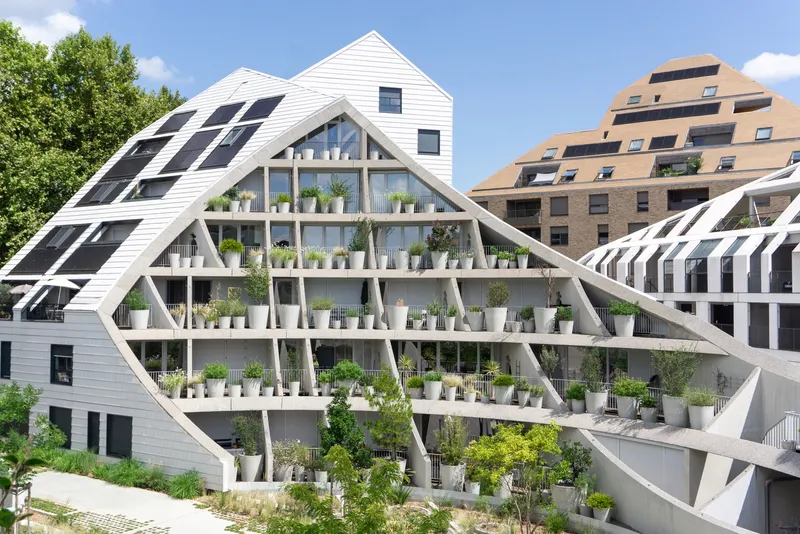 Triangular facade with diagonal concrete frame and staggered planters on terraced balconies under blue sky