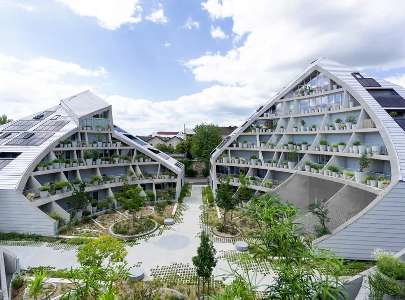 Courtyard view between two gabled volumes with planted terraces and circular garden beds