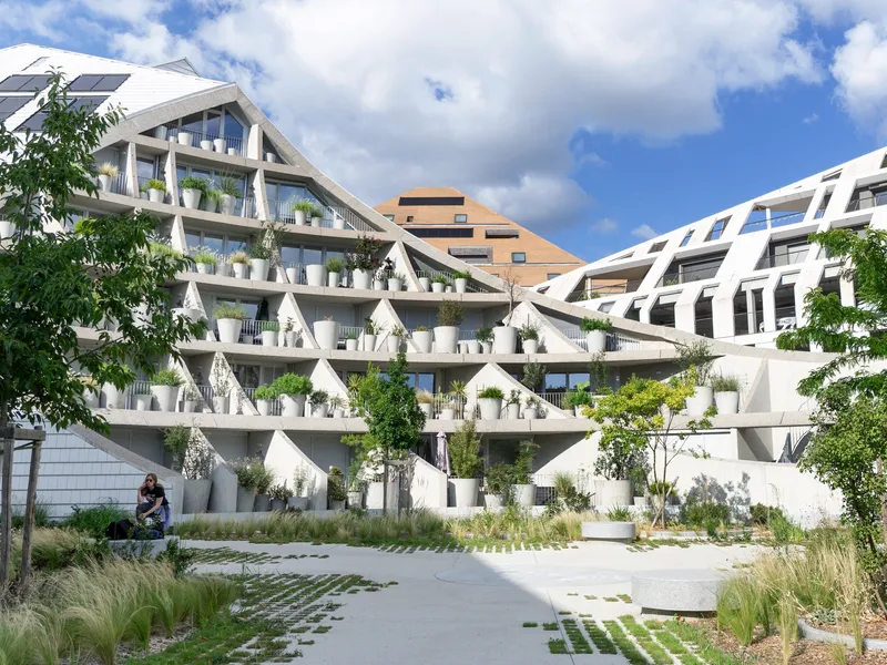 Pedestrian courtyard with permeable paving and planted grasses leading to the diagonal frame facade