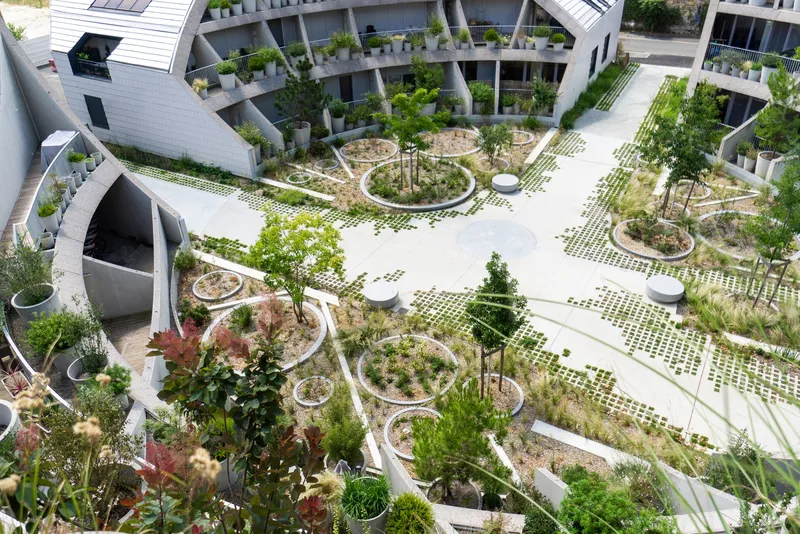 Aerial view of a central courtyard with circular planted beds and perforated paving surrounded by residential balconies