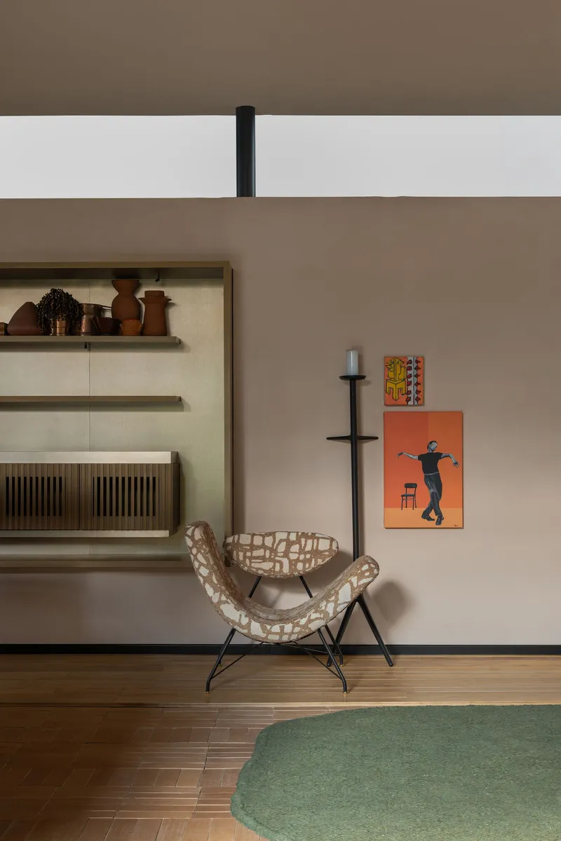 Woven lounge chair beside a black floor candelabra against a warm taupe wall