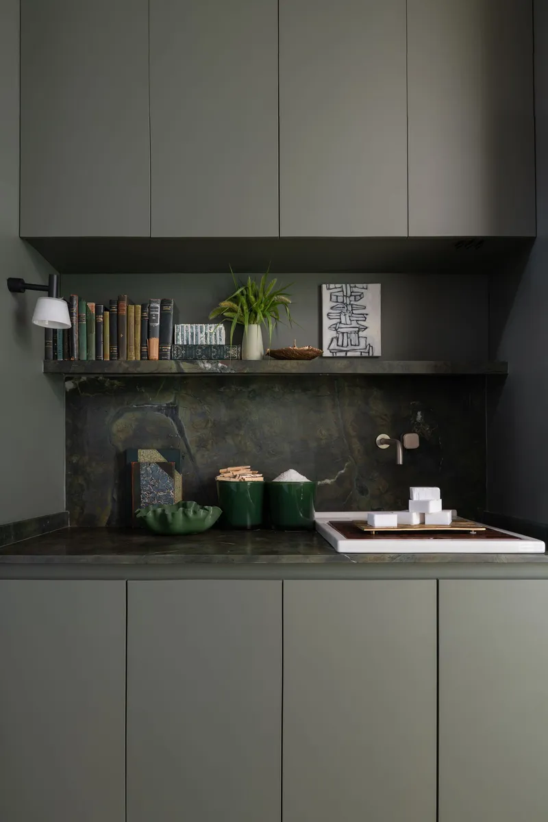 Kitchen nook with dark stone backsplash and floating shelf beneath grey upper cabinets