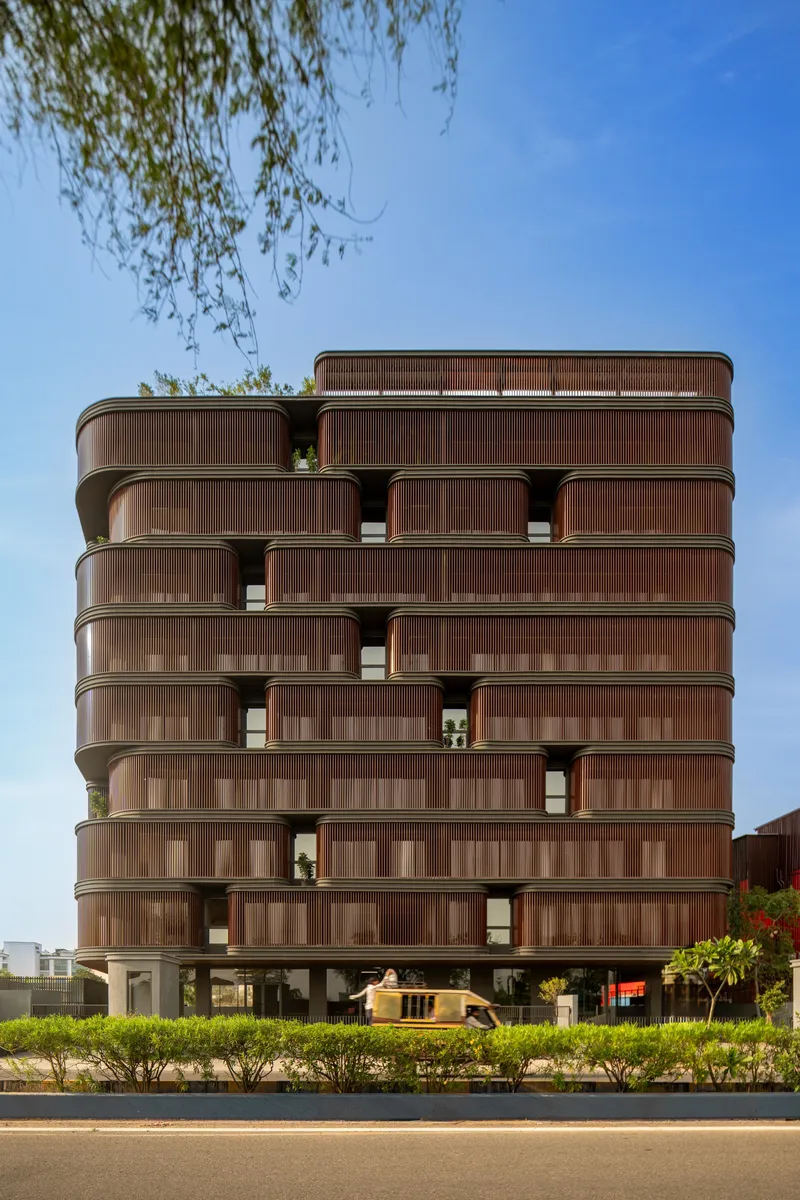 Street view of the residential building with rounded balconies and willow branches overhead