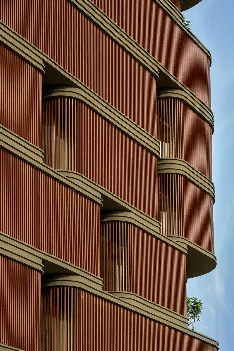 Close-up of the ribbed terracotta facade panels wrapping around curved balcony edges