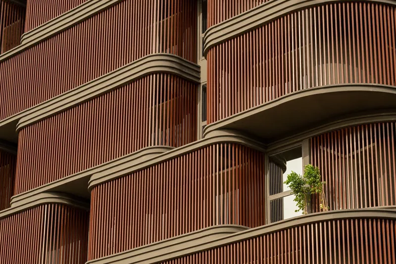 Close-up of the vertical timber slat screens wrapping the rounded balcony edges with potted plants