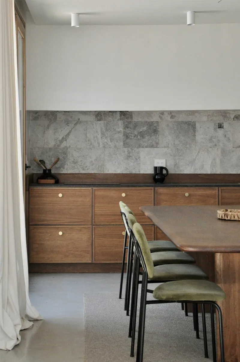 Dining area with walnut cabinetry, stone backsplash, and timber table with upholstered chairs