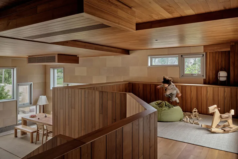 Upper level play area with vertical wood paneling and stairwell railing in afternoon sun