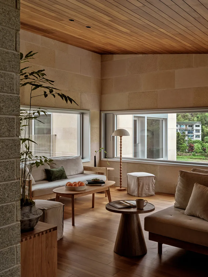 Living room with horizontal stone block walls and timber ceiling beside a potted bamboo plant