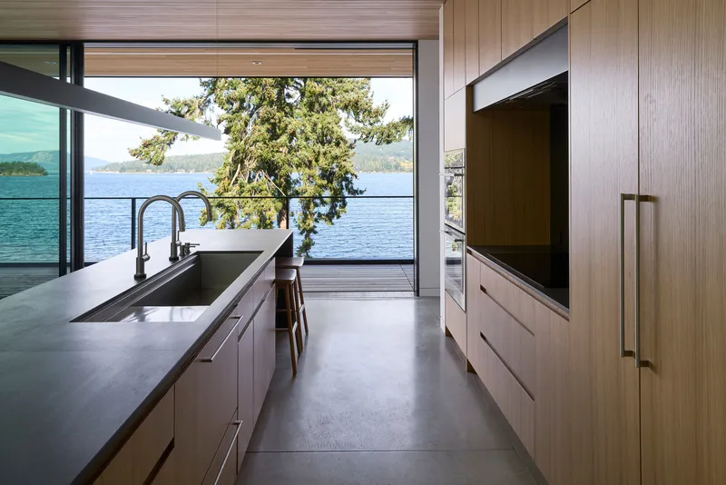 Kitchen island with integrated sink opening to a lakeside terrace framed by an overhanging tree