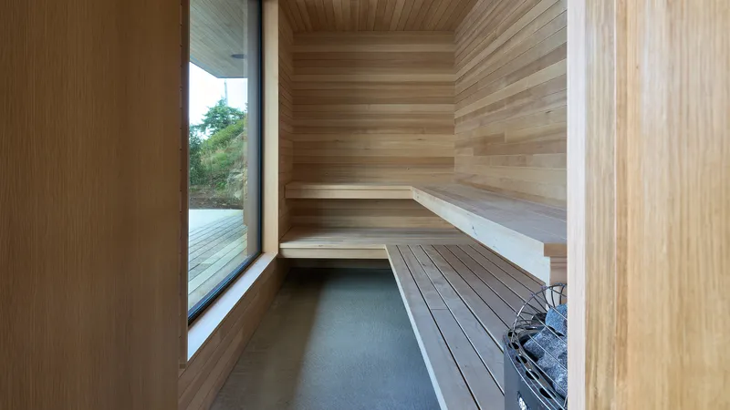 Timber-clad sauna with stepped benches and a narrow window opening to the deck outside
