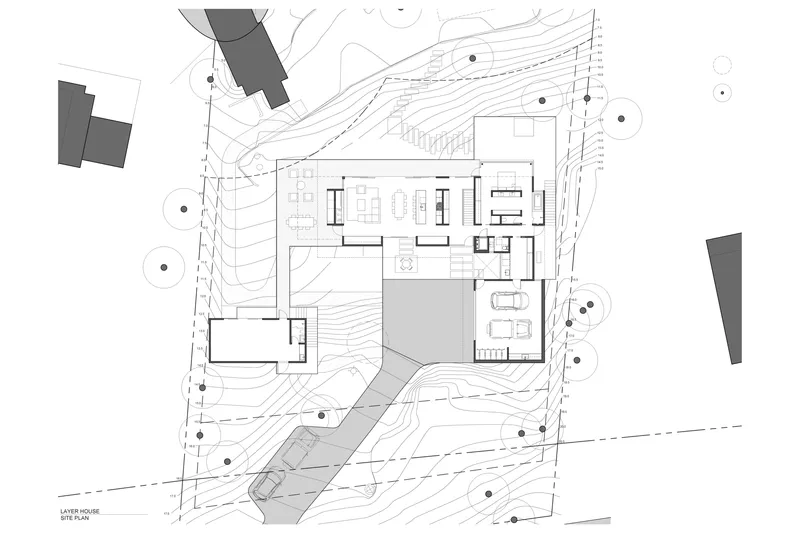 Site plan drawing showing residence on sloped terrain with topographic contours and trees