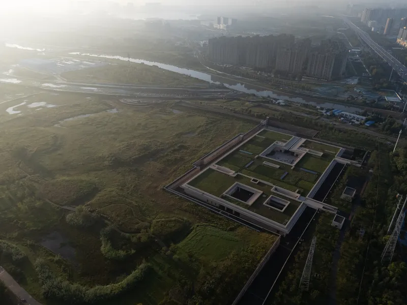 Aerial perspective of the walled compound with rectangular courtyards and low rooflines in hazy morning light