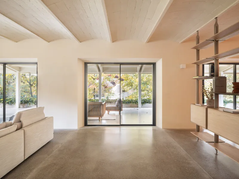 Living room with exposed timber ceiling beams and sliding glass doors opening to a terrace