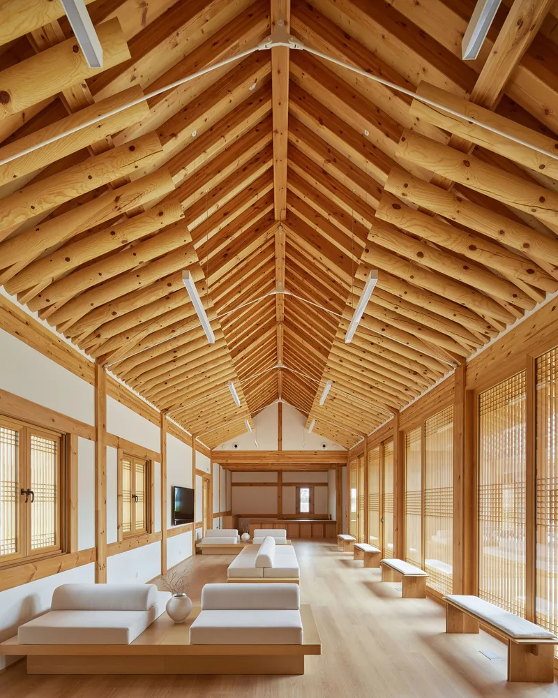 Interior hall with exposed timber vault ceiling, latticed screens, and raised platform seating along both sides