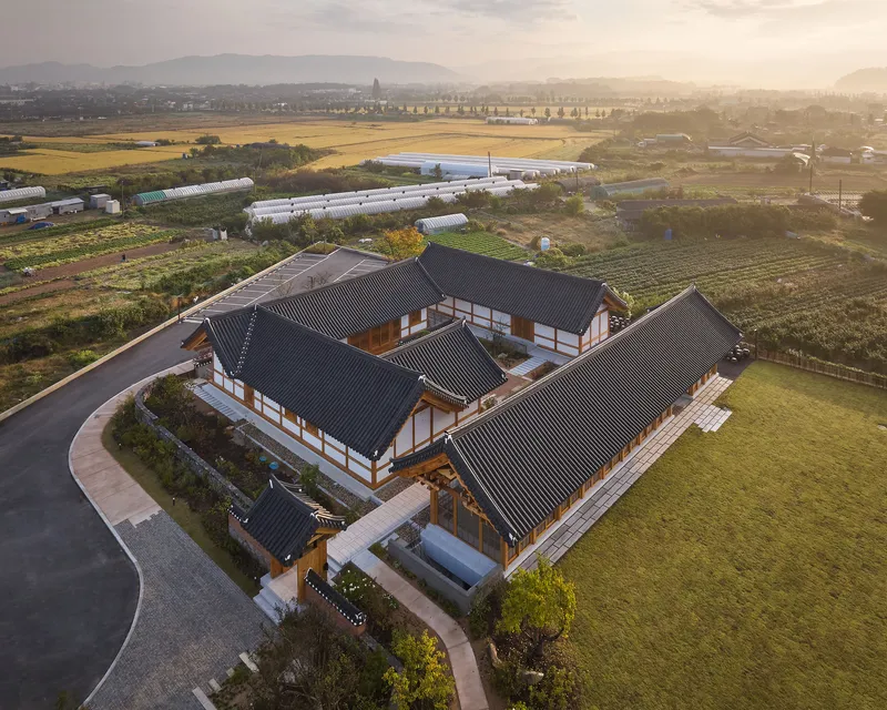Drone view of the compound surrounded by agricultural fields and greenhouses at golden hour