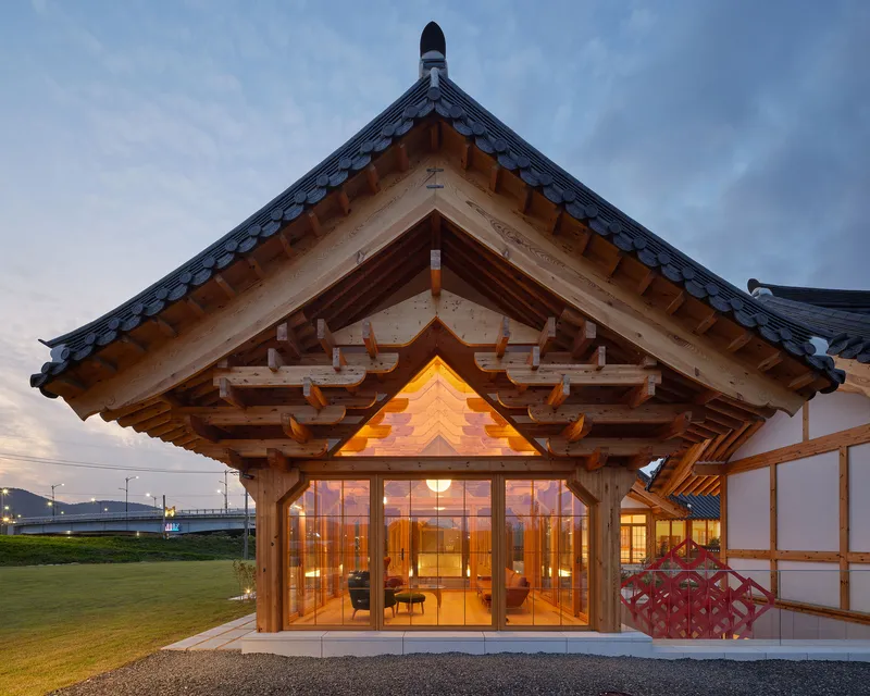 Glazed entrance beneath a timber gabled roof with exposed bracketing at dusk