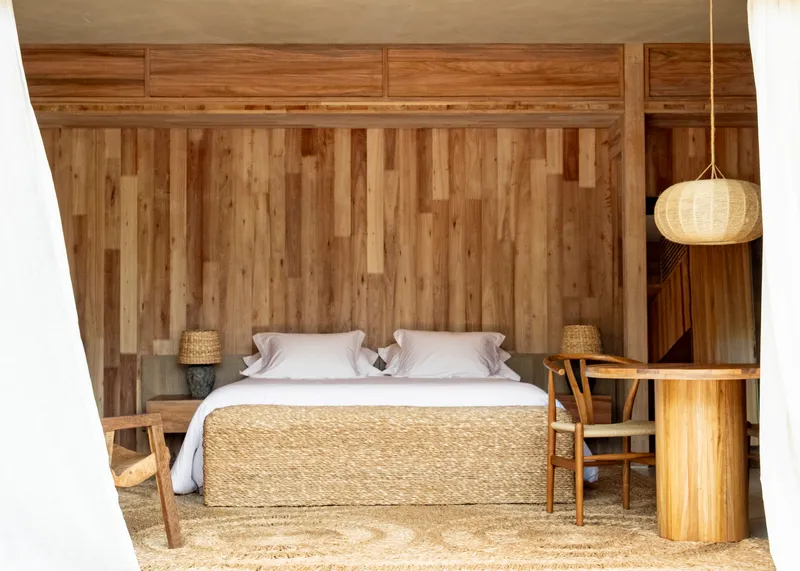 Built-in bed niche framed by vertical wood panels and a woven pendant light hanging overhead