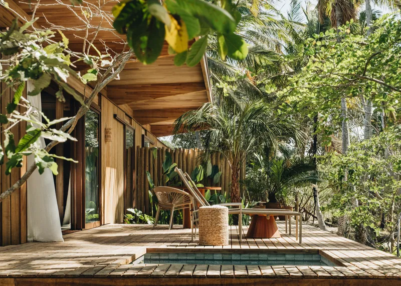 Wooden deck with shallow pool bordered by vertical slatted facade and dense tropical plantings