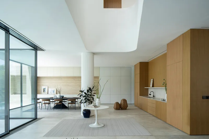 Open living space with curved ceiling cutout and oak cabinetry along one wall