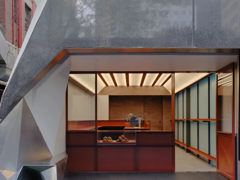 Street view of the folding glass storefront with timber ceiling beams and dark grey textured facade