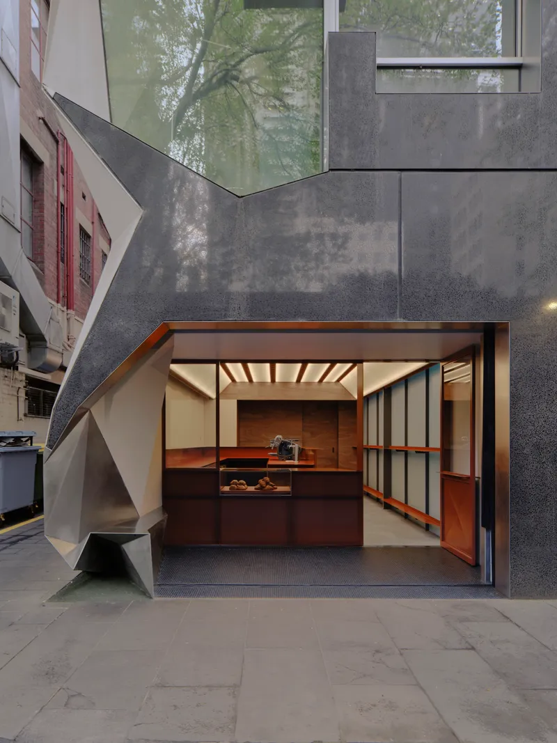 Fully opened storefront with display counter beneath exposed timber beams at dusk