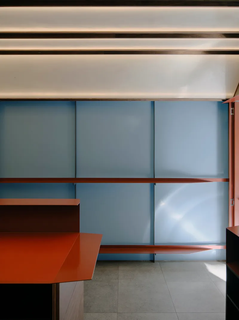 Interior view of the translucent sliding screens with red metal shelving in filtered daylight