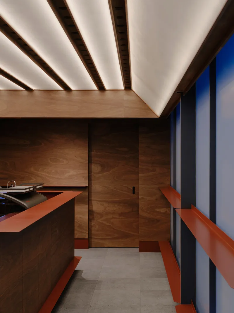 Interior showing the timber paneled wall and exposed ceiling beams lit from above
