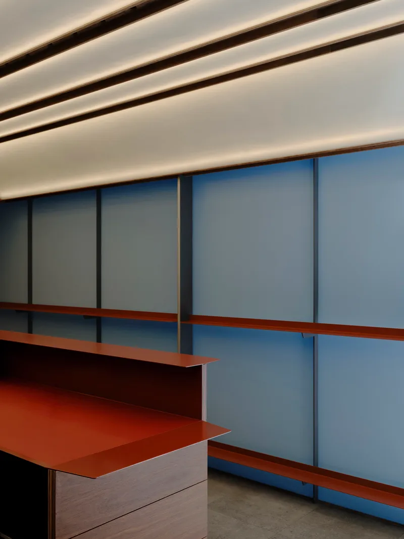 Copper shelf and timber counter against a wall of frosted glass panels framed in wood
