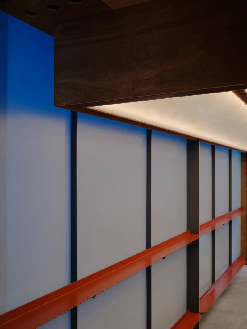 Dark timber volume suspended above the frosted glass wall with integrated ceiling lighting