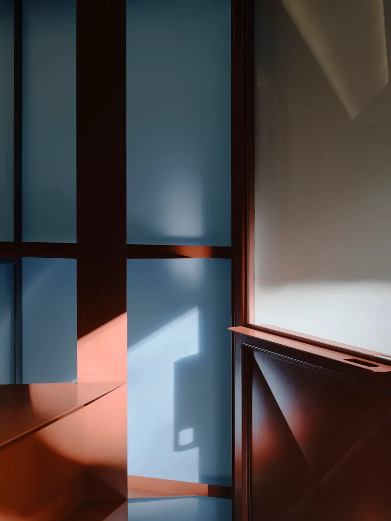 Interior corner with dark timber framing and frosted glass panels casting warm afternoon light