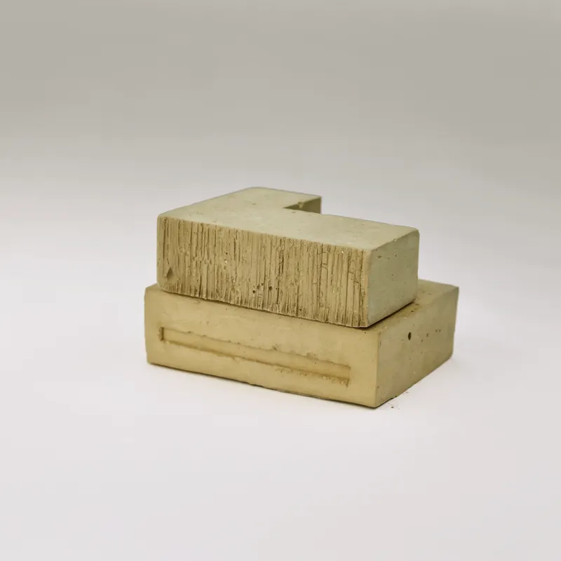 Physical model in concrete showing two stacked volumes with board-formed texture on white backdrop