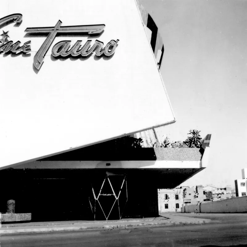 Detail of the cantilevered canopy and signage against the white facade with a palm tree visible beyond