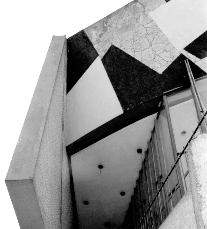 Upward view of a cantilevered volume with diamond-patterned soffit and diagonal black beams