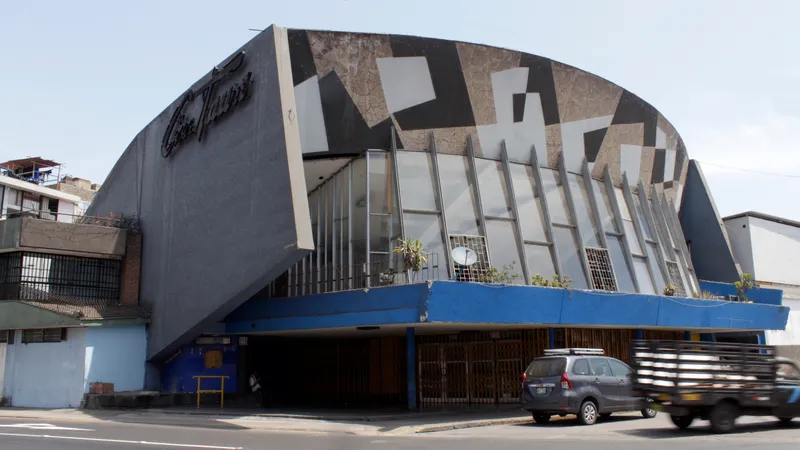 Street view of the barrel-vaulted facade with vertical fins and geometric stone pattern under daylight