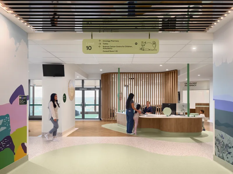 Reception area with curved timber slat screen and terrazzo flooring with visitors at the desk
