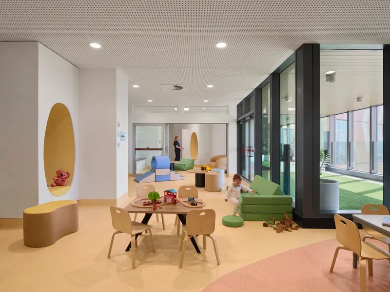 Play area with timber furniture, oval wall alcove, and glazed courtyard doors with a child on the floor