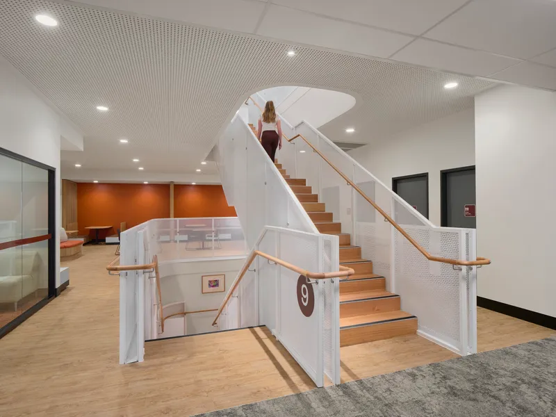 Curved staircase with timber treads, white perforated balustrades and timber handrails leading to upper level