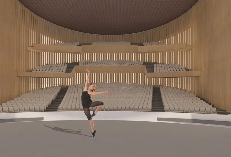 Interior view of tiered seating with vertical timber battens and a dancer performing on the stage below