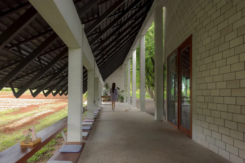 Covered walkway with white columns and diagonal timber roof structure as a person walks through
