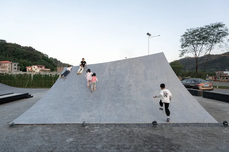 Children climbing the inclined concrete roof surface at twilight with hills in the background