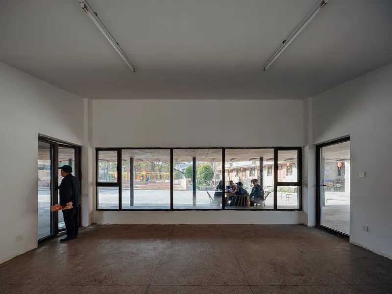 White interior room with continuous horizontal window opening overlooking the street and a person by the door