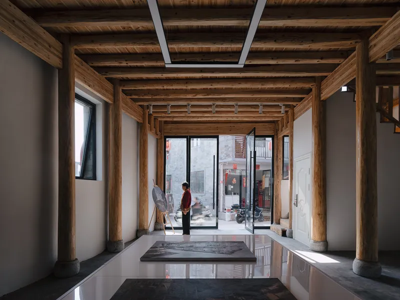 Interior hall with exposed timber columns and beams, polished floor and two figures in conversation
