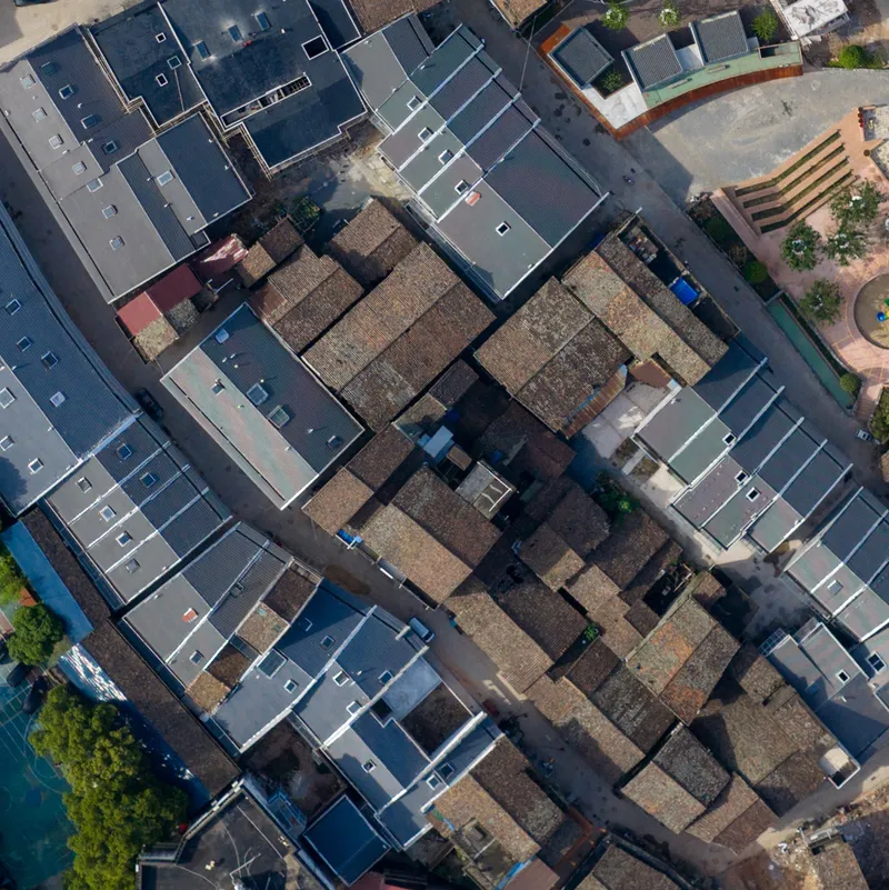 Aerial view of traditional tile rooftops enclosed by new construction with grey roofs